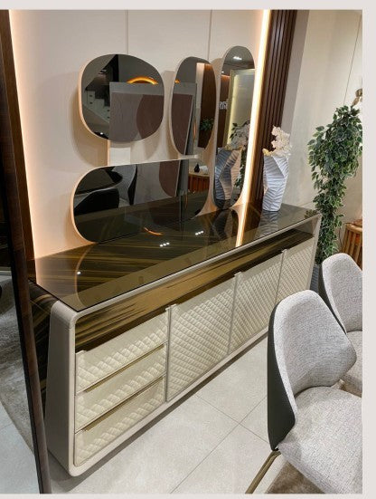 The Nile Luxuries modern sideboard with cream quilted drawers and doors, dark wood veneer top, and gold accents. Display cabinet with smoked glass doors.