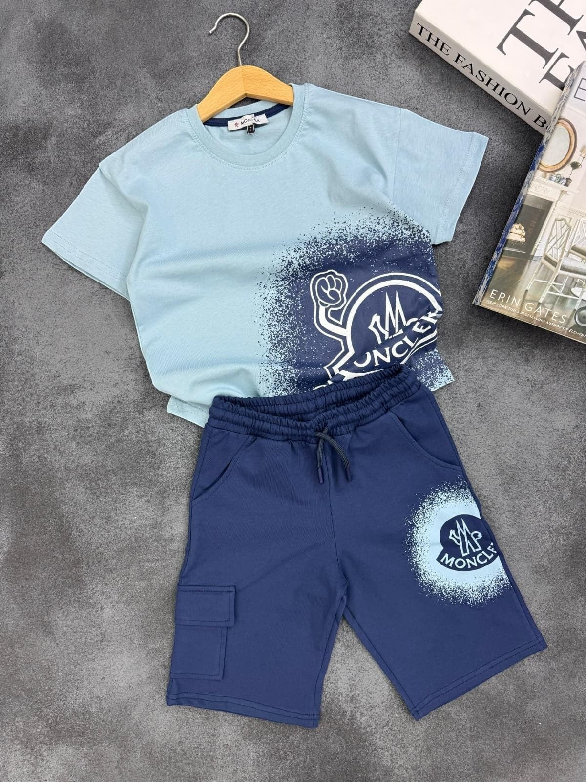 The Nile Luxuries Moncler kids two-piece set with light blue graphic t-shirt and navy cargo shorts with drawstring.