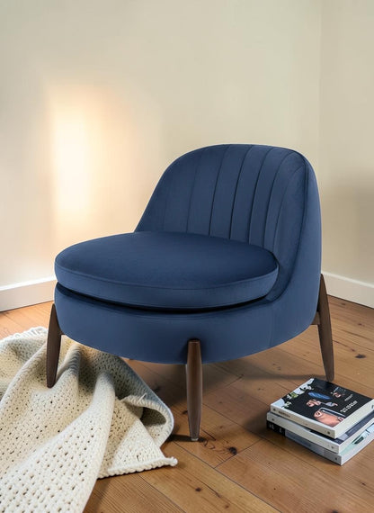 The Nile Luxuries deep navy blue velvet accent armchair with channel tufting and tapered wooden legs.