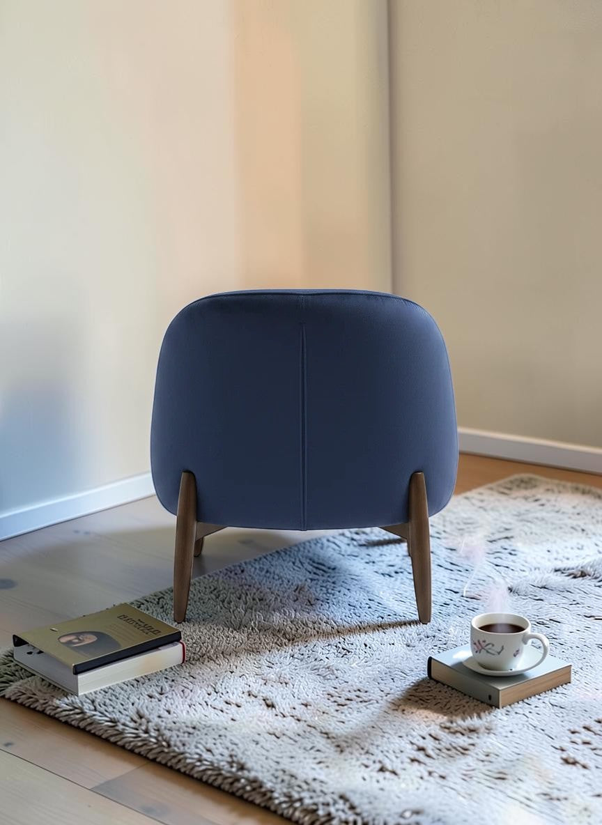The Nile Luxuries deep navy blue velvet accent armchair with rounded silhouette and tapered wooden legs.