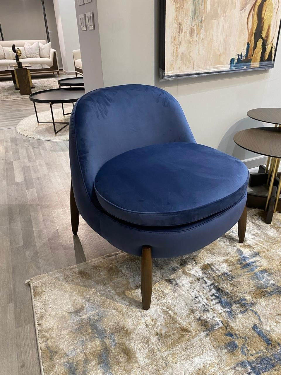The Nile Luxuries deep navy blue velvet accent armchair with rounded silhouette and tapered wooden legs.