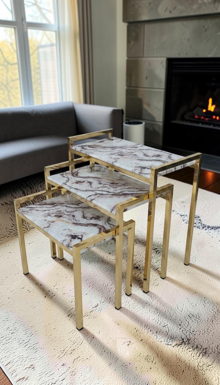 The Nile Luxuries set of 3 nesting tables with white and burgundy marble-effect tops and gold metal frames.