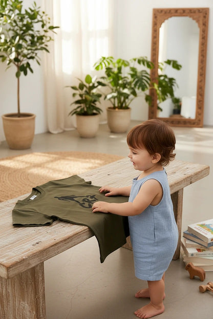 The Nile Luxuries olive green graphic t-shirt with CR7 football print displayed on a wooden table next to a toddler.