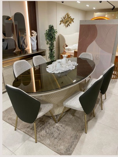 The Nile Luxuries oval dining table with upholstered chairs featuring gold legs. Modern dining set.
