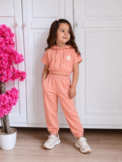 The Nile Luxuries girls peach short-sleeve cropped hoodie and jogger set with a daisy graphic and side pockets.