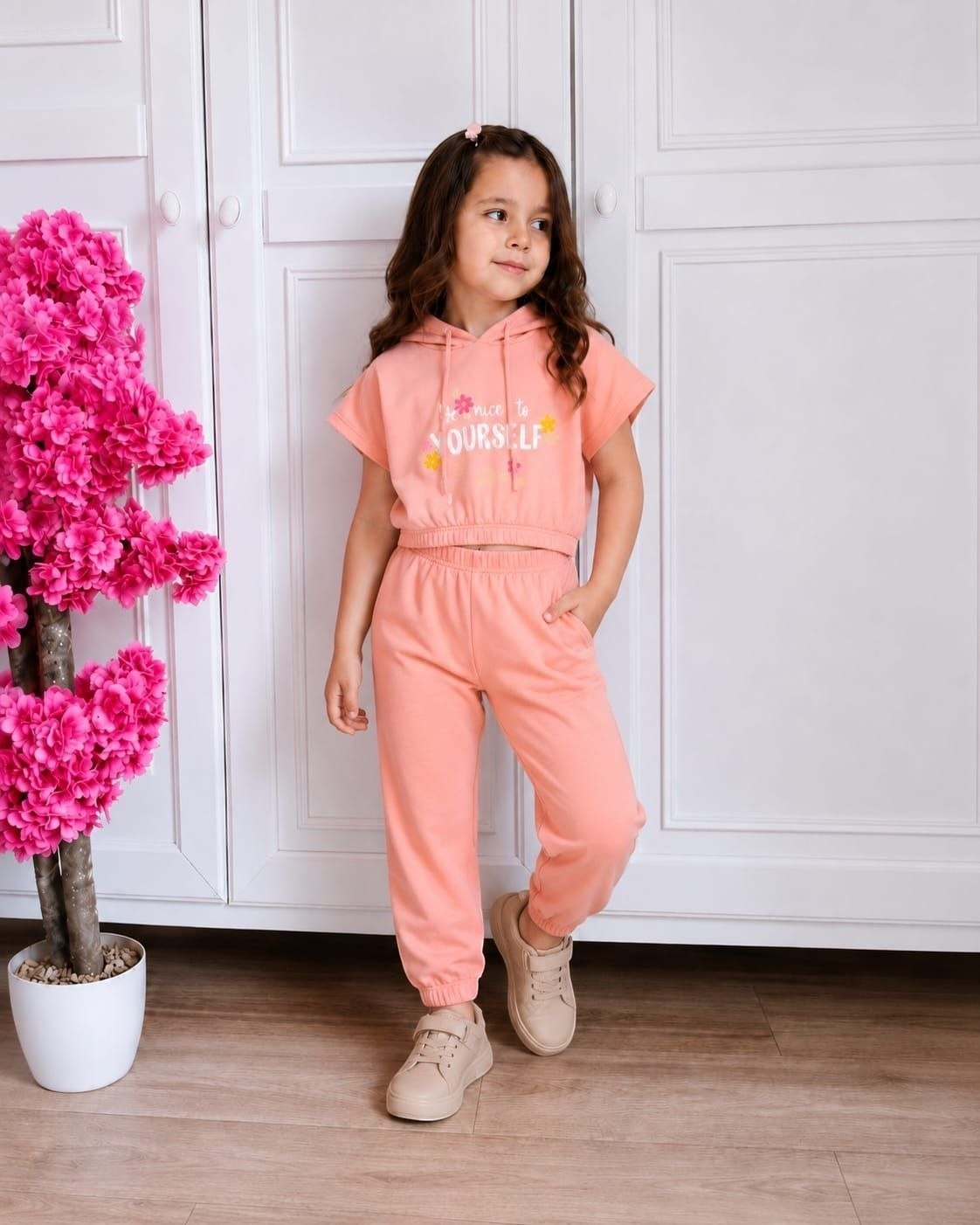 The Nile Luxuries girls peach short sleeve hoodie and jogger set with floral graphic worn by a young girl
