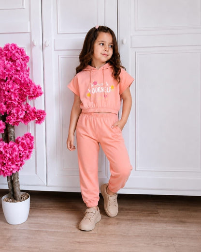 The Nile Luxuries girls peach short sleeve hoodie and jogger set with floral graphic worn by a young girl