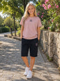 The Nile Luxuries cotton lounge set with a dusty pink crew-neck t-shirt and black drawstring shorts on a young woman.