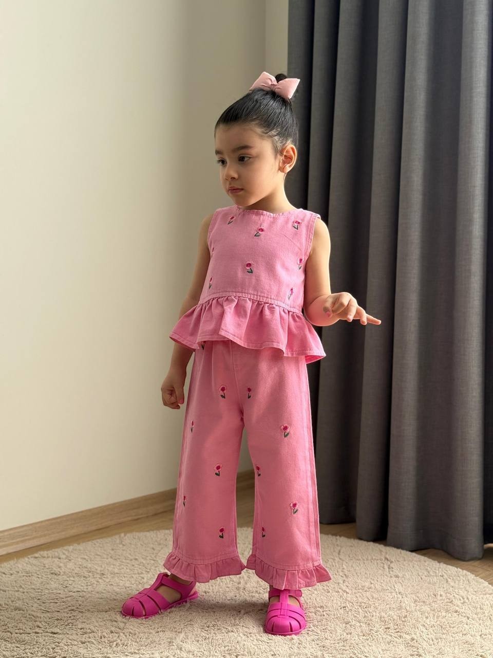 The Nile Luxuries pink denim peplum top and wide-leg trouser set with floral embroidery worn by a young girl.