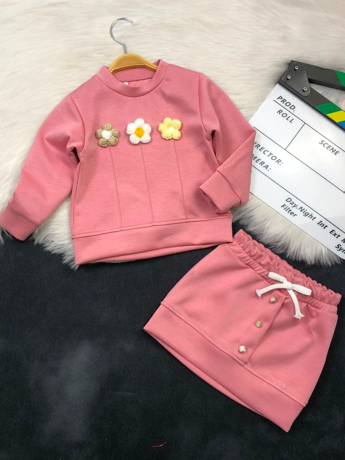 The Nile Luxuries pink girls sweatshirt and skirt set with textured floral appliques and decorative button details.