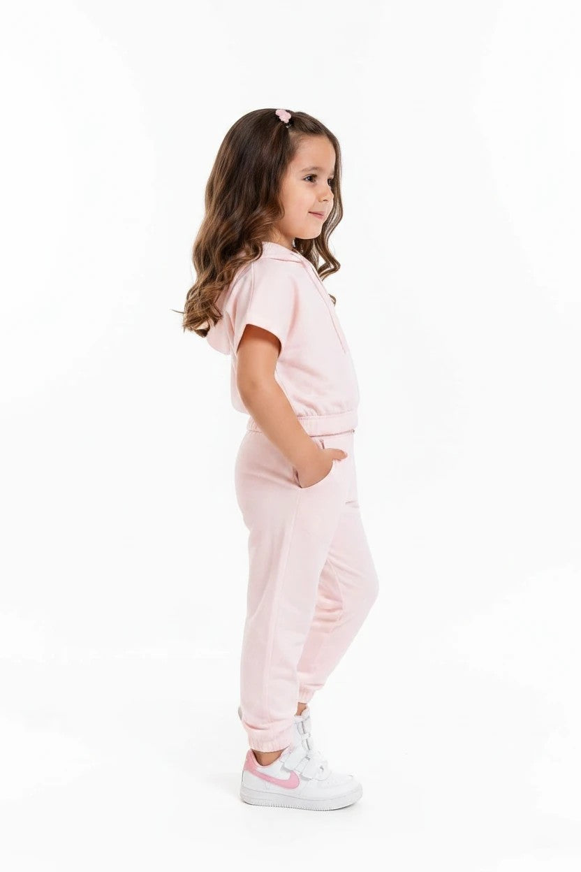 A young girl wearing a soft pink short-sleeve hoodie and matching jogger set from The Nile Luxuries