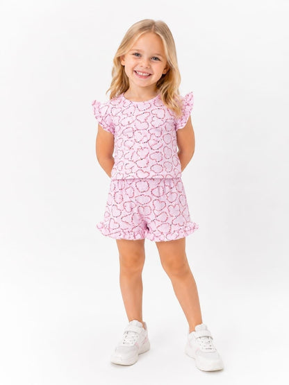 The Nile Luxuries girls pink heart print lounge set with flutter sleeves and ruffled shorts on a smiling young girl.