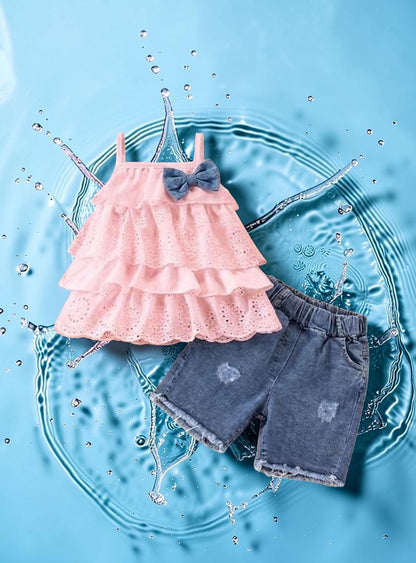 The Nile Luxuries pink tiered eyelet ruffle tank top with denim shorts and a blue bow accent.