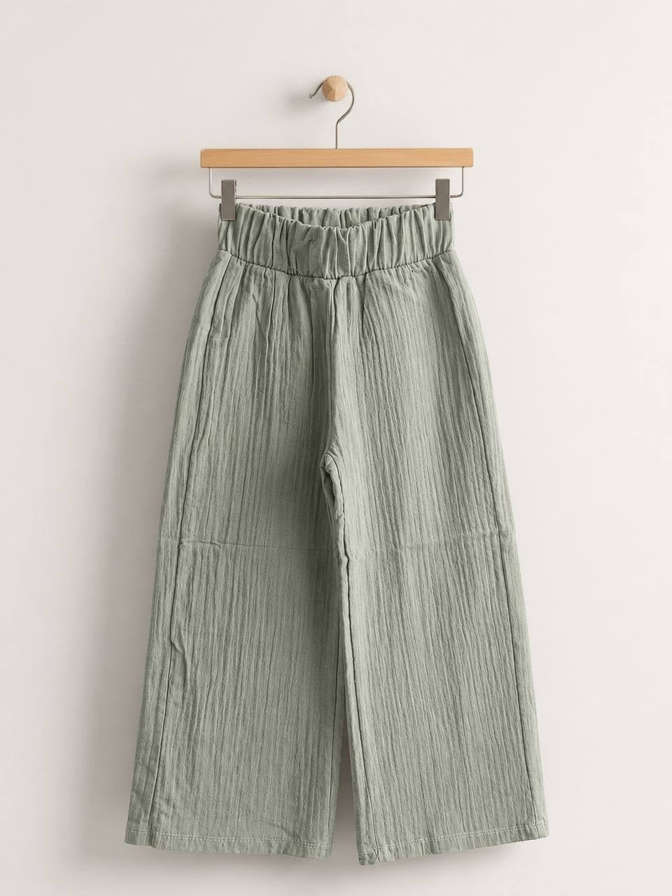 The Nile Luxuries sage green wide-leg trousers in crinkled cotton muslin with a high-rise elasticated waistband.