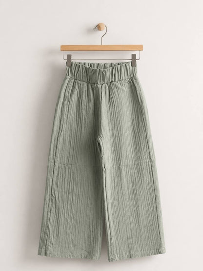 The Nile Luxuries sage green wide-leg trousers in crinkled cotton muslin with a high-rise elasticated waistband.