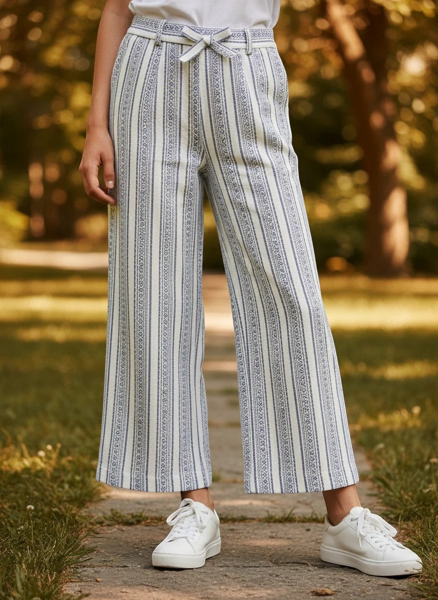 The Nile Luxuries girls wide-leg trousers featuring blue and white vertical stripes with geometric patterns and a tie waist