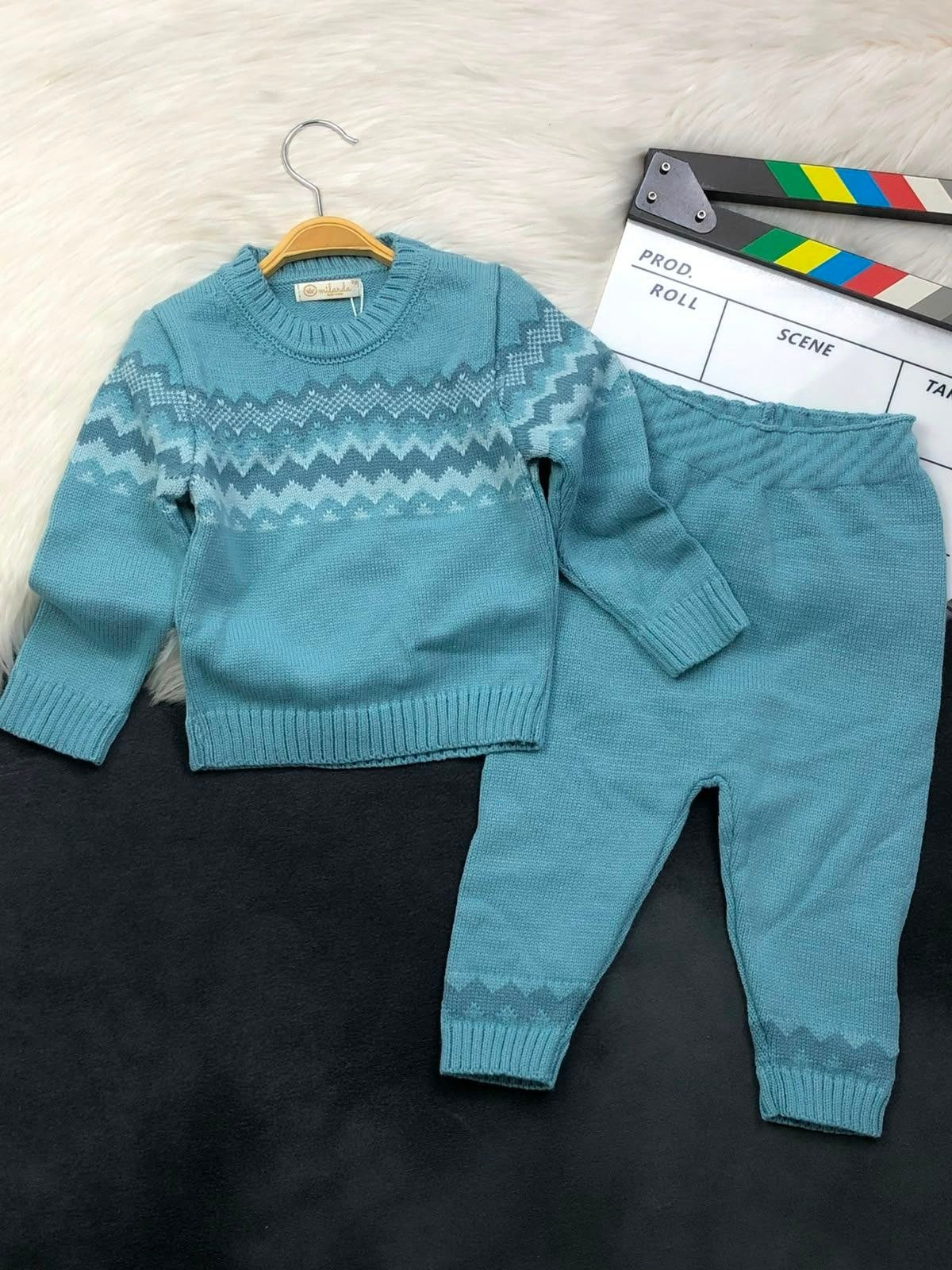 The Nile Luxuries teal knitted sweater and pant set featuring a chevron pattern on the chest and ribbed cuffs.