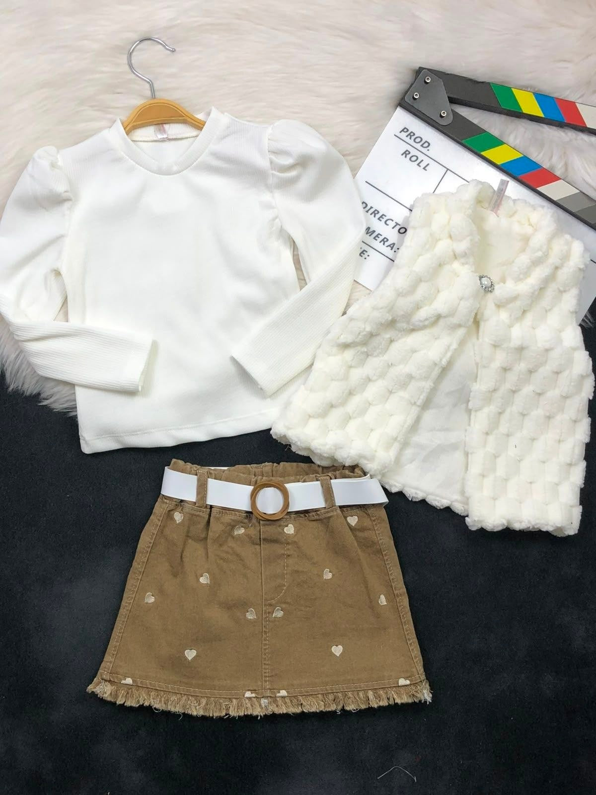 The Nile Luxuries three-piece set with a white ribbed top, faux-fur vest, and brown heart-embroidered denim skirt.