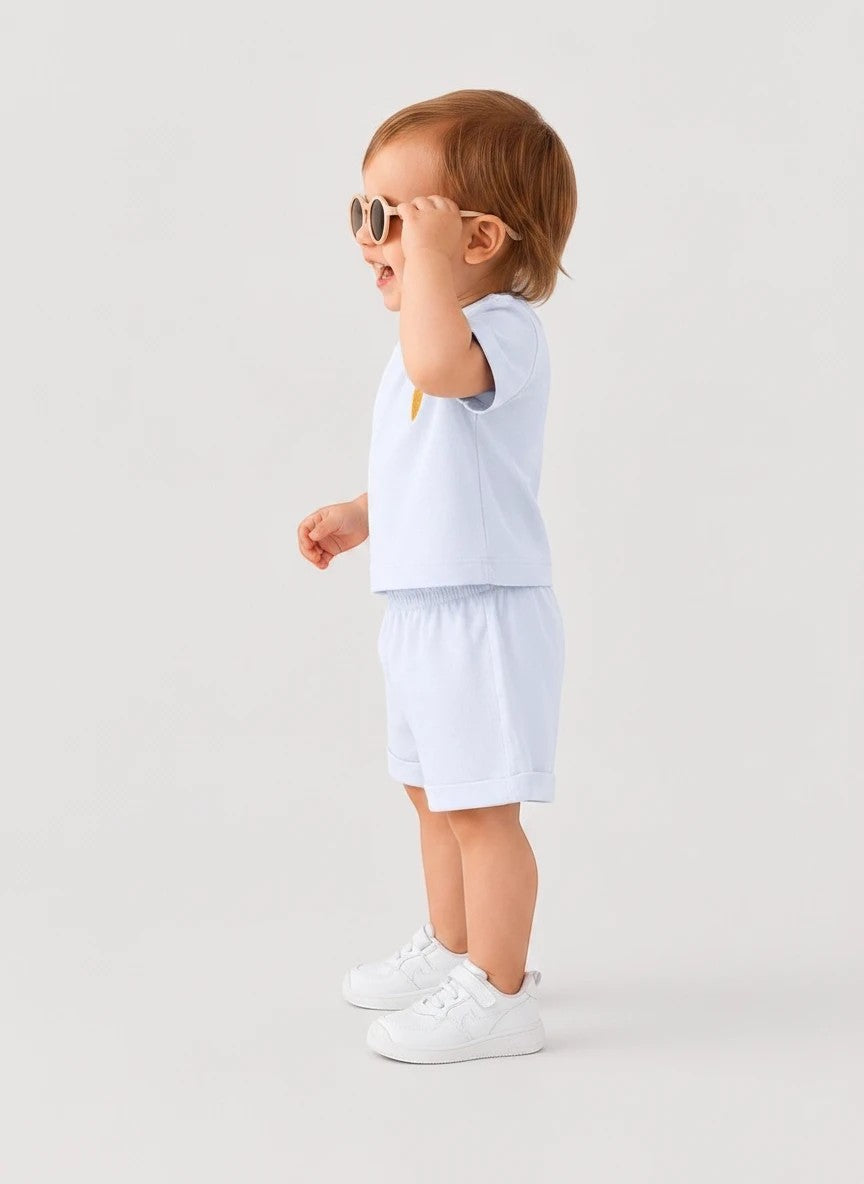 The Nile Luxuries toddler light blue short sleeve shirt and shorts set with embroidered carrot detail on a child.