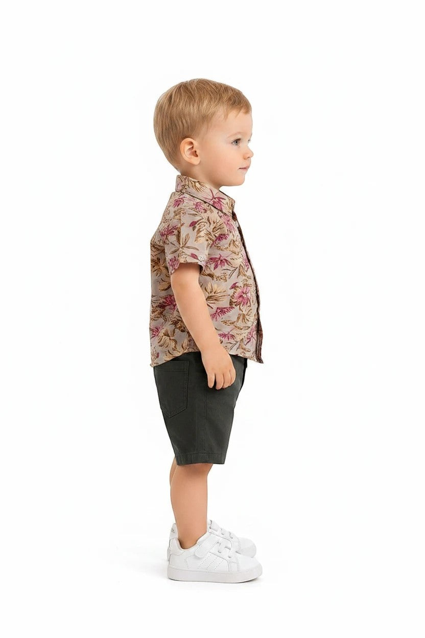 Toddler boy wearing The Nile Luxuries floral button-down shirt and olive green shorts with white sneakers