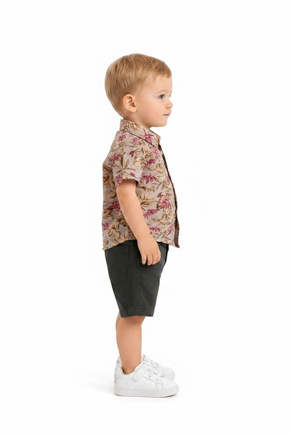 Toddler boy wearing The Nile Luxuries floral button-down shirt and olive green shorts with white sneakers