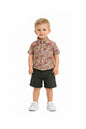 Toddler boy wearing The Nile Luxuries floral button-down shirt and olive green shorts with white sneakers