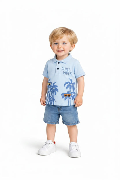 Toddler boy wearing The Nile Luxuries light blue tropical polo shirt with palm trees and denim shorts on white background
