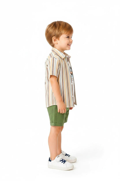 Toddler boy wearing The Nile Luxuries striped button-down shirt, graphic tee, and green shorts on a white background.