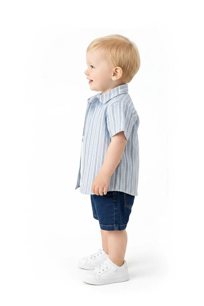 Toddler boy wearing The Nile Luxuries striped short-sleeve button-down shirt and denim shorts with white sneakers.