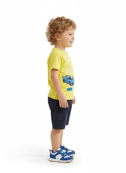 The Nile Luxuries toddler boy wearing a yellow sports car graphic t-shirt and navy blue cargo shorts, side view.