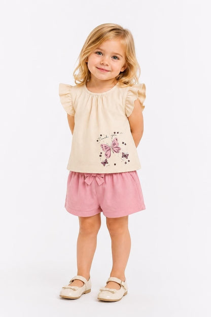 Toddler girl wearing The Nile Luxuries beige flutter sleeve top with butterfly print and pink bow-detail shorts.