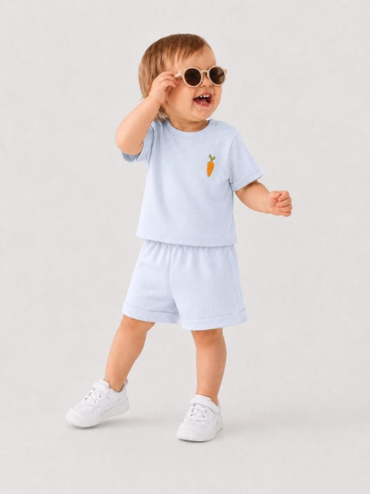 Toddler wearing The Nile Luxuries light blue short sleeve shirt and shorts set with an embroidered carrot detail.