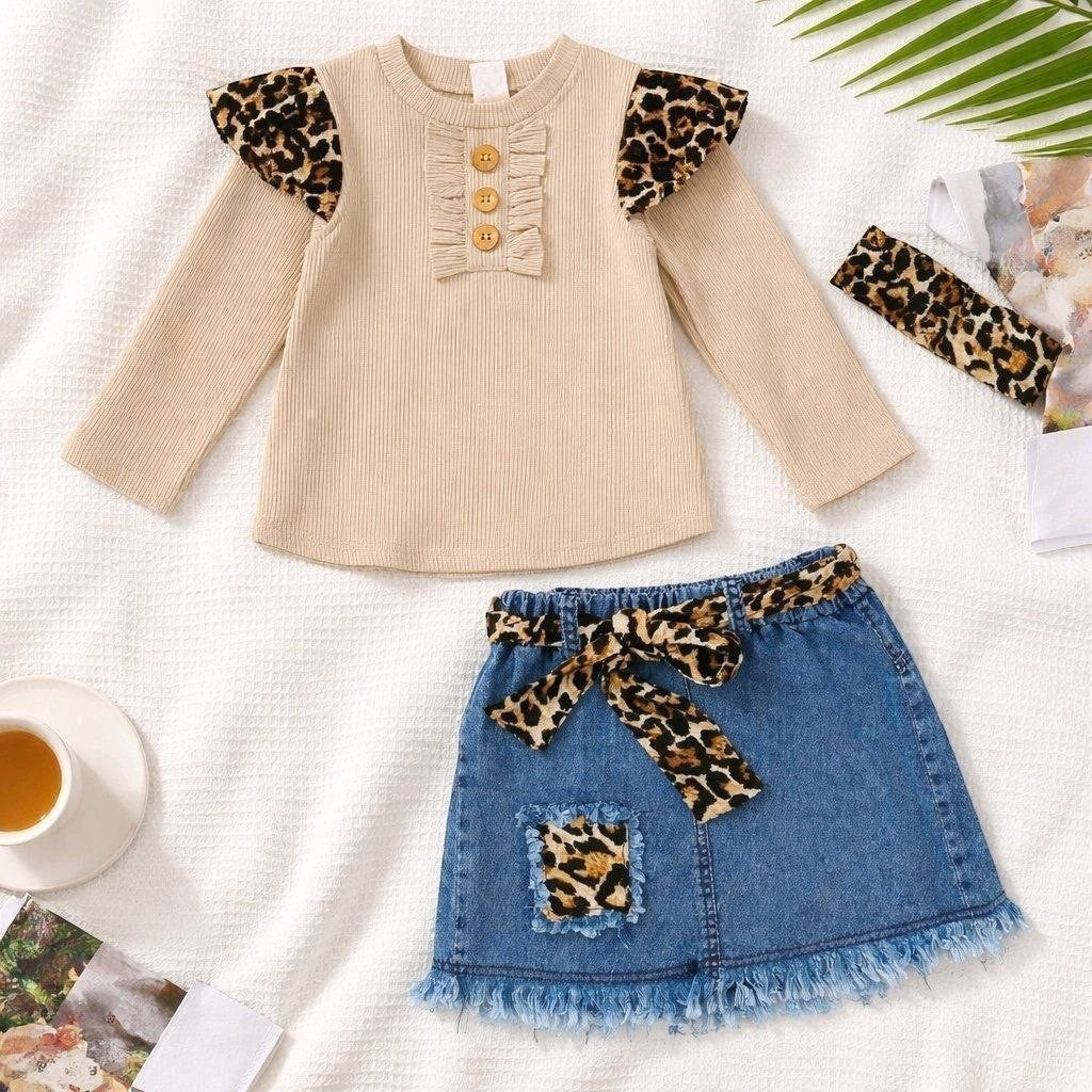 The Nile Luxuries toddler girl outfit with beige ribbed long-sleeve top, denim skirt, and leopard print accessories.
