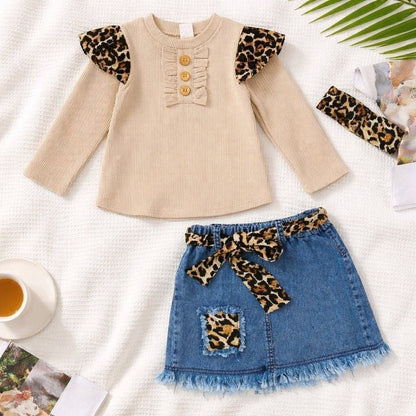 The Nile Luxuries toddler girl outfit with beige ribbed long-sleeve top, denim skirt, and leopard print accessories.