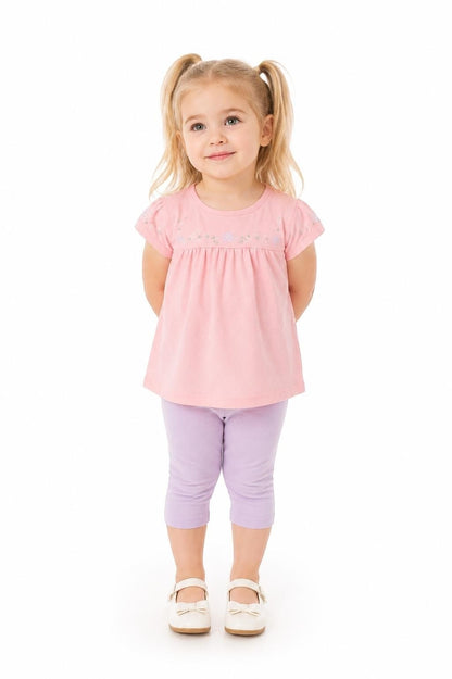 Toddler girl wearing The Nile Luxuries pink embroidered top and purple capri leggings against a white background.