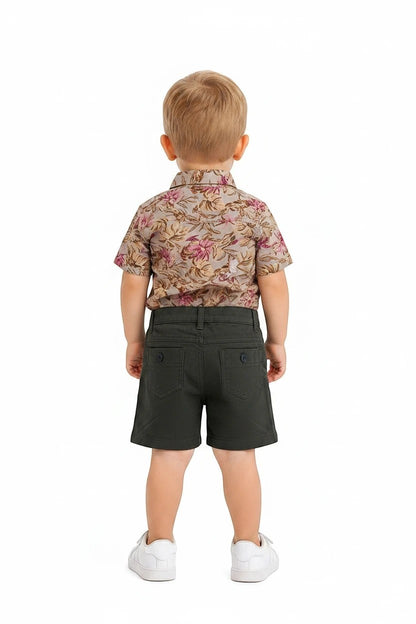 Toddler boy wearing The Nile Luxuries floral button-down shirt and olive green shorts with white sneakers