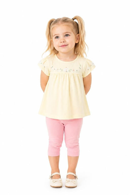 Toddler girl wearing The Nile Luxuries yellow floral embroidered top and pink capri leggings against white background