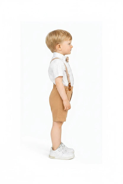 Toddler boy wearing The Nile Luxuries formal set with white patterned shirt, tan shorts, bow tie, and suspenders.