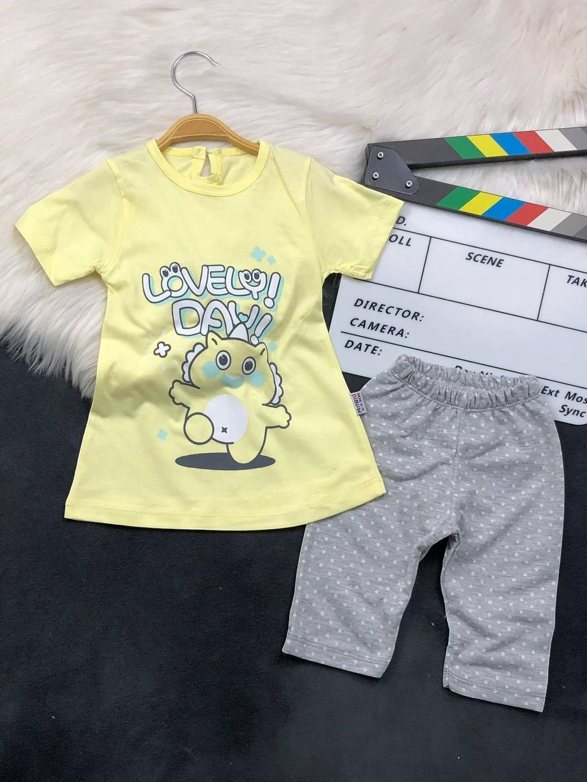 The Nile Luxuries toddler set with a yellow graphic t-shirt and grey polka-dot leggings on a white fur background.