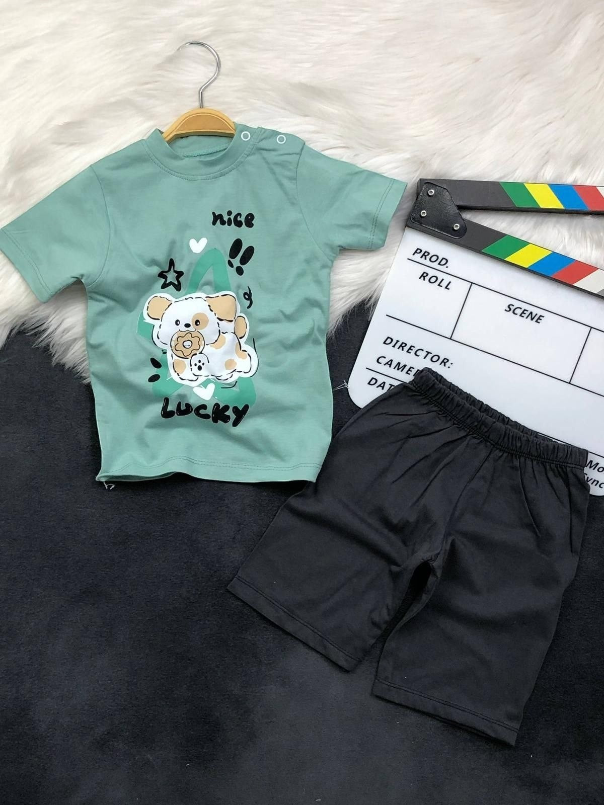 The Nile Luxuries toddler set with a sage green puppy graphic t-shirt featuring shoulder snaps and black shorts.