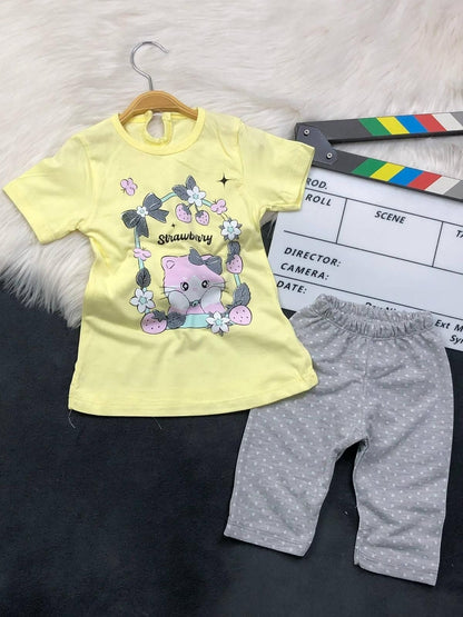 The Nile Luxuries toddler set with a yellow kitten graphic t-shirt and grey polka dot pants on a white faux fur rug.