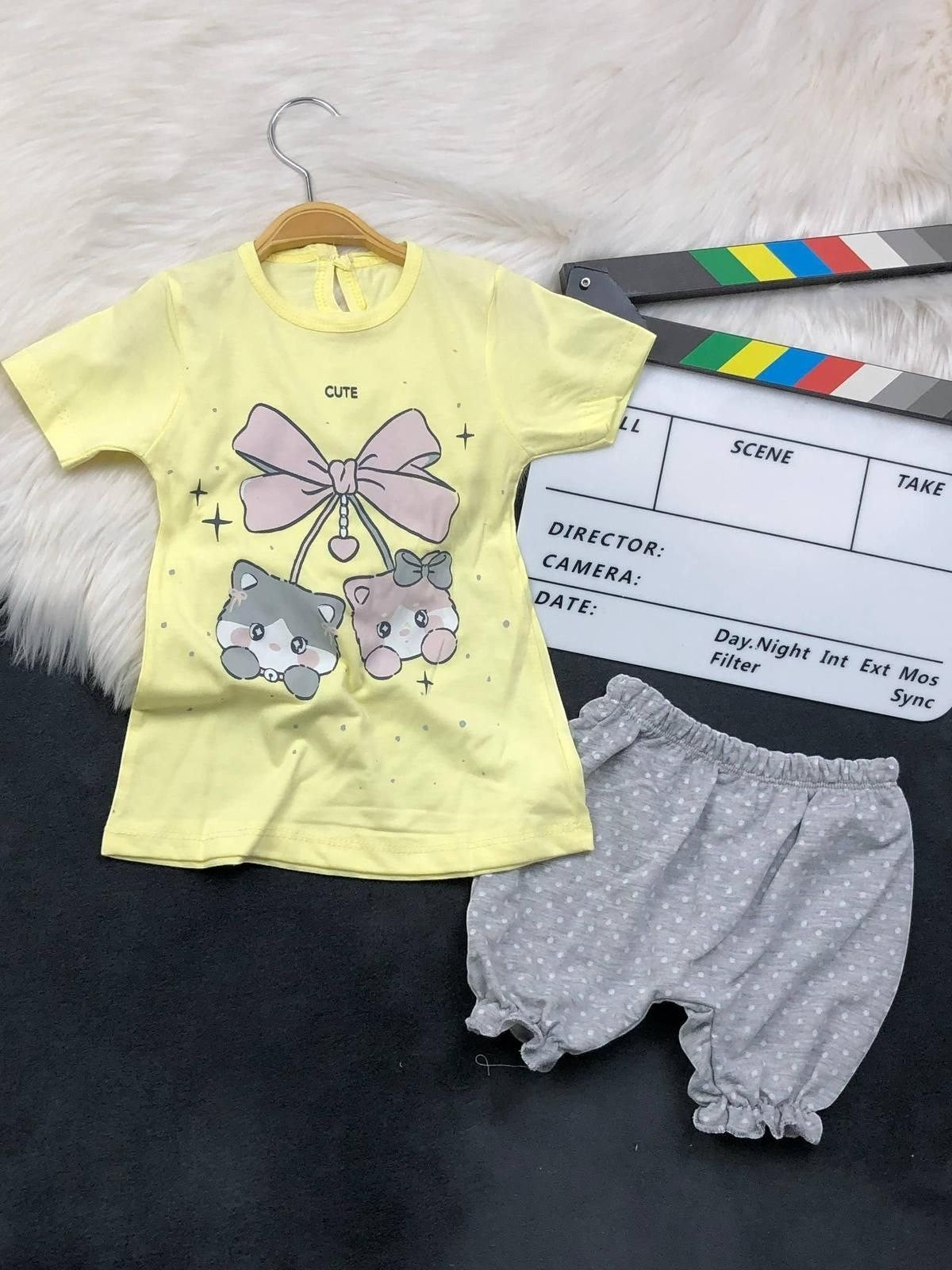The Nile Luxuries toddler set featuring a yellow kitten graphic t-shirt with a bow and grey polka-dot ruffled bloomers.