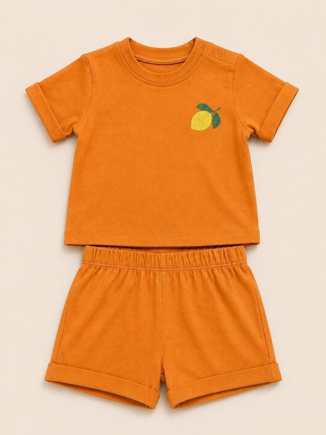 The Nile Luxuries toddler two-piece set in burnt orange with a lemon embroidery, crewneck top, and elastic shorts.