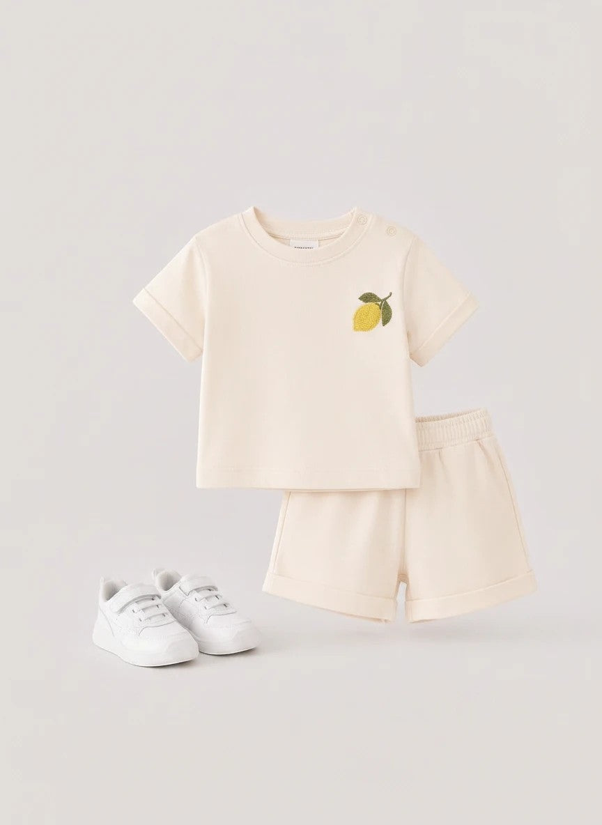 The Nile Luxuries toddler cream short sleeve shirt and shorts set with lemon embroidery and shoulder snap closures.