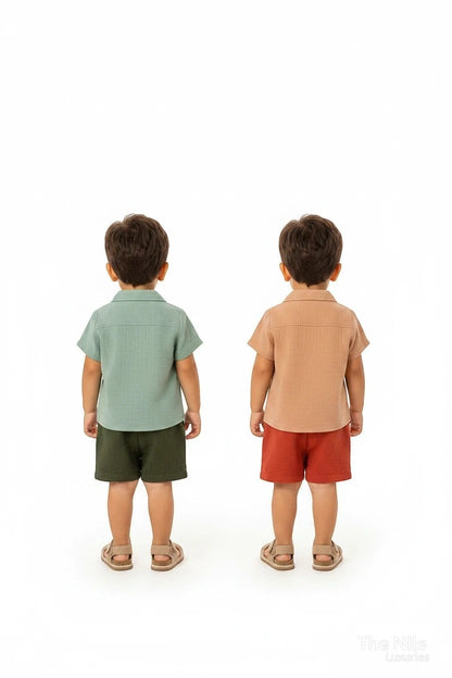Two toddlers wearing The Nile Luxuries muslin shirt and shorts sets in sage green and earthy terracotta tones.