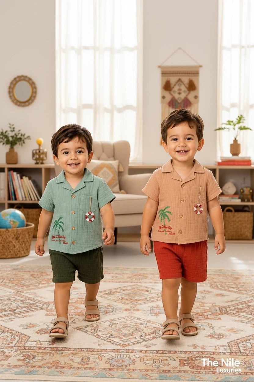 Two toddlers wearing The Nile Luxuries muslin summer sets with palm tree embroidery and lifebuoy charms.
