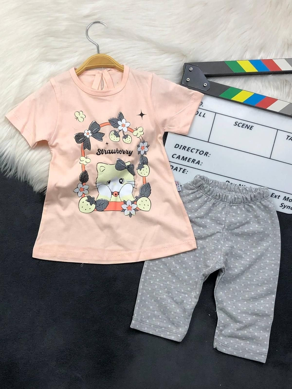 The Nile Luxuries toddler pajama set with a peach kitten graphic t-shirt and grey polka dot pants.