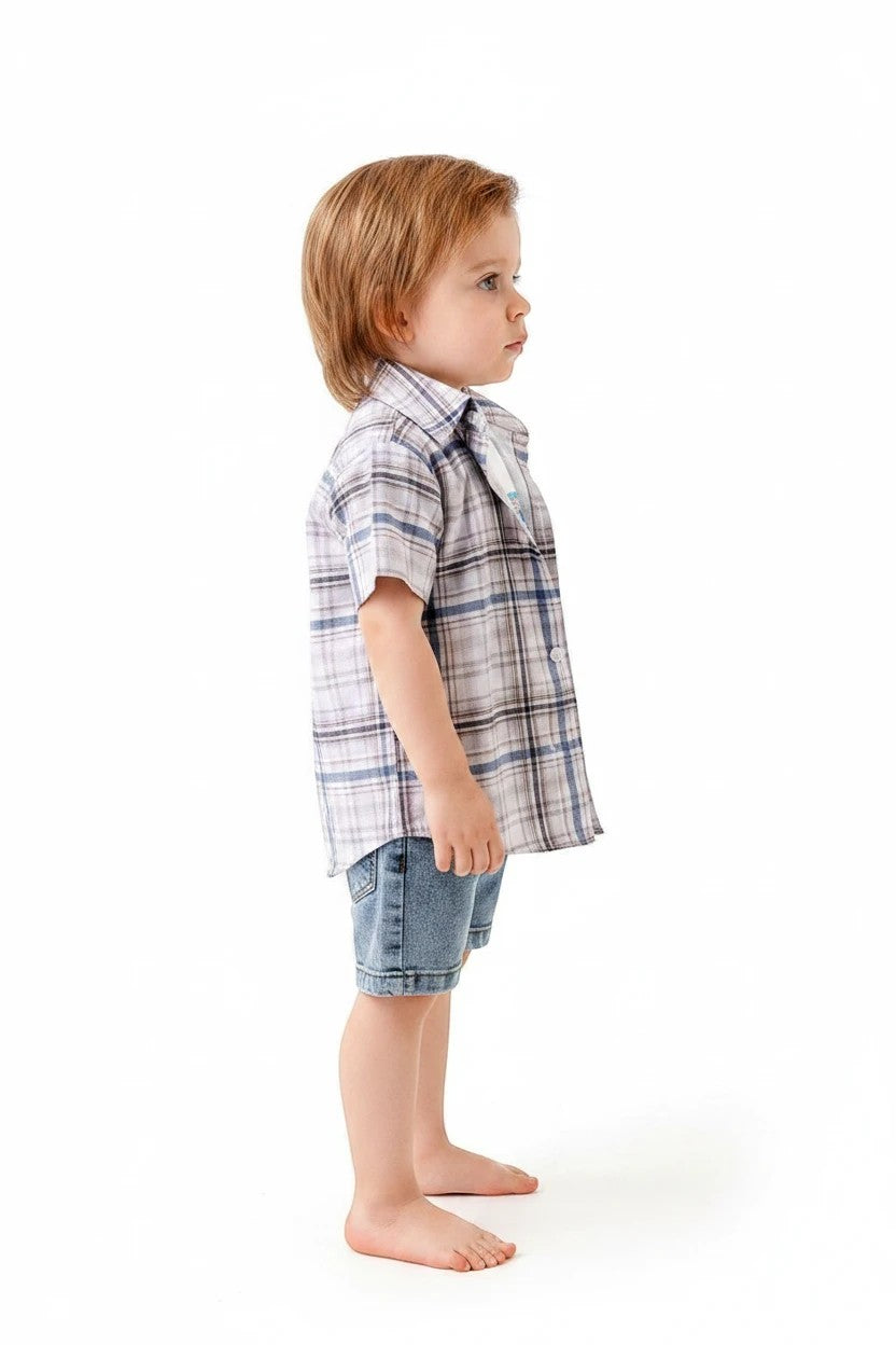 Toddler boy wearing The Nile Luxuries plaid short-sleeve button-down shirt and denim shorts on white background