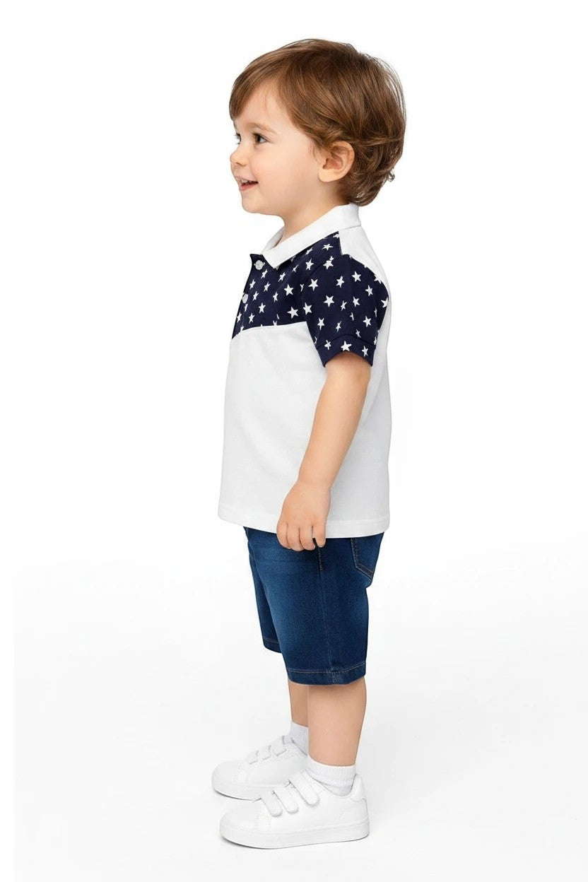 Toddler boy wearing The Nile Luxuries white polo shirt with navy star sleeves and denim shorts against white background
