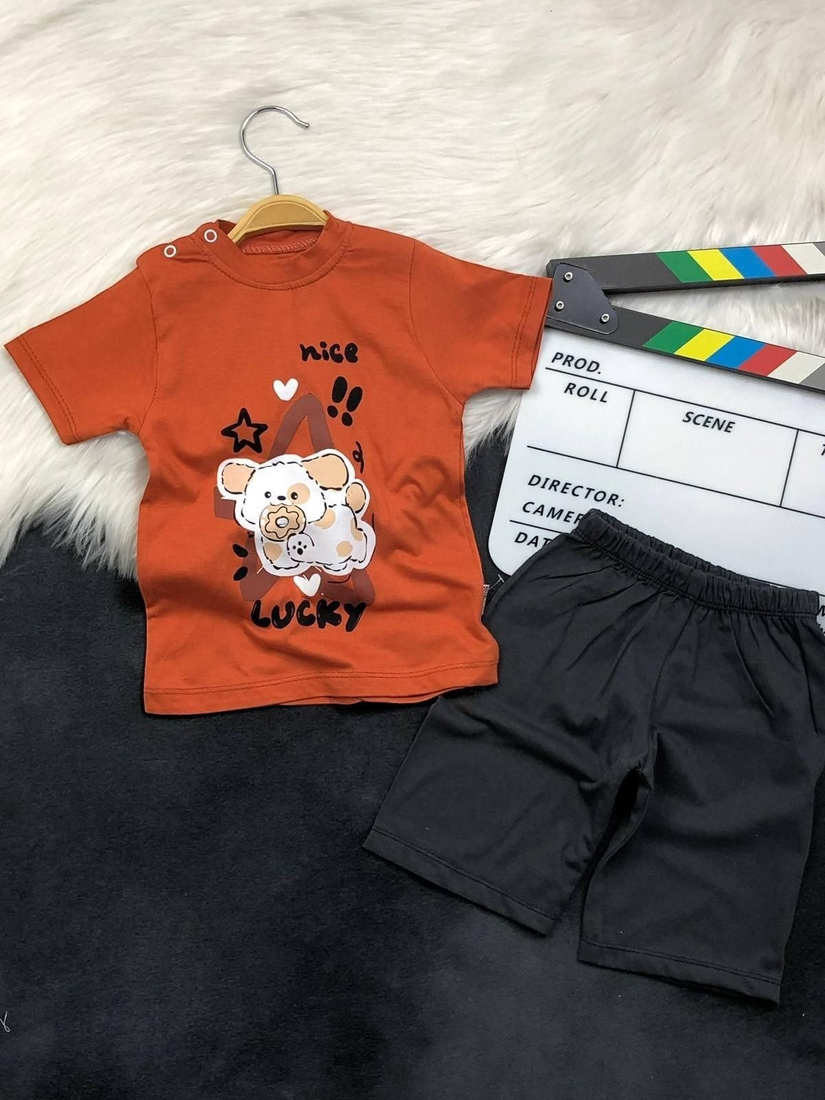 The Nile Luxuries toddler set with a rust orange puppy graphic t-shirt and black shorts featuring shoulder snaps.
